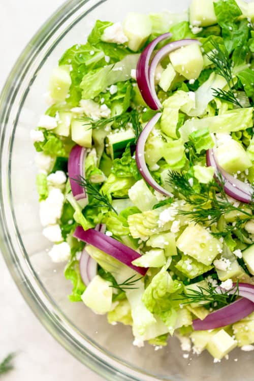 Salade hachée avec de la laitue romaine, fromage Feta, concombres, oignon rouge et aneth avec une simple vinaigrette au vin rouge. Une salade facile à accompagner de tous vos plats méditerranéens.